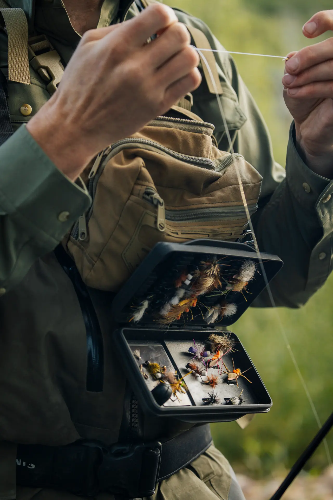 Angler tying on a fly from an open Redband Fly Box